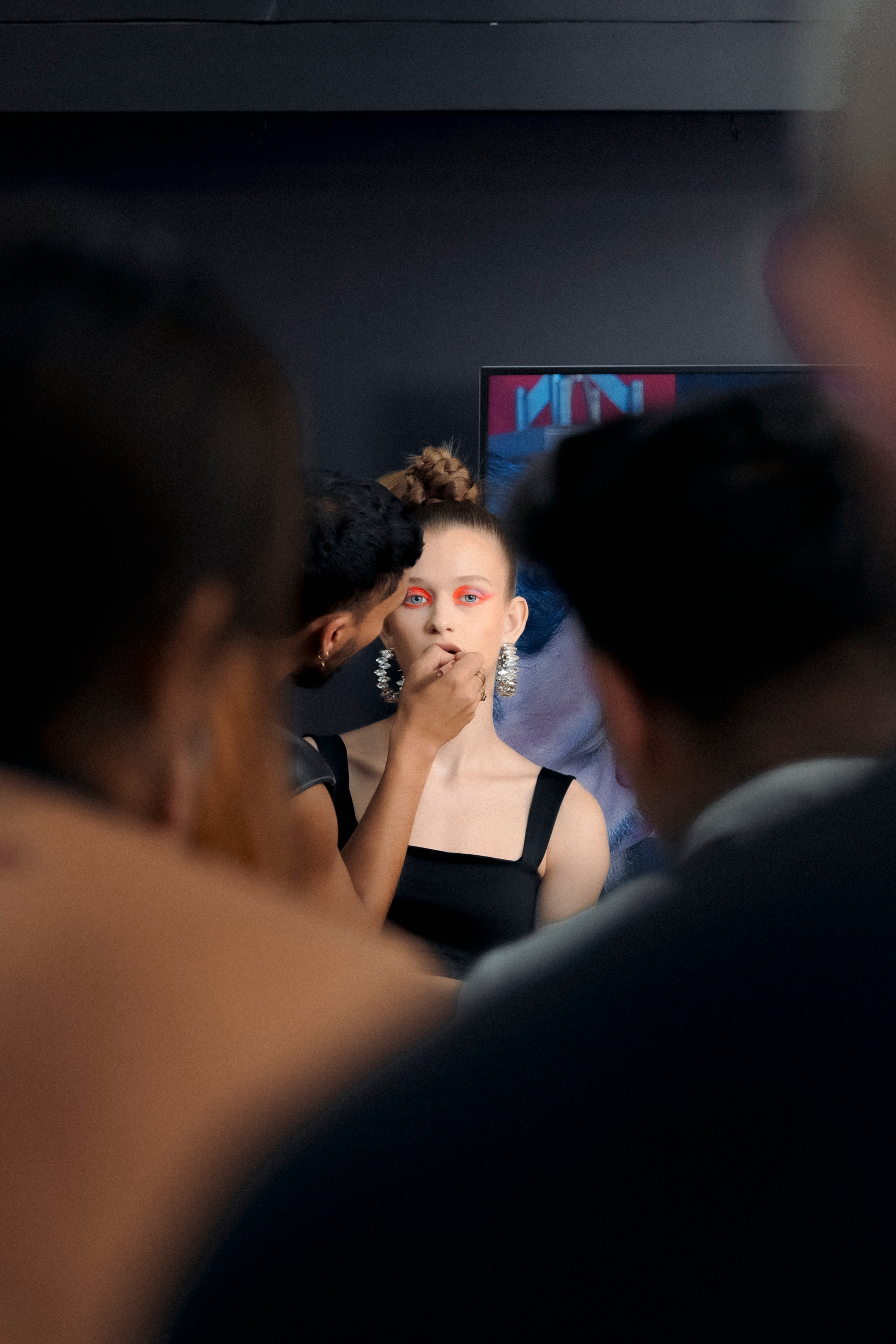 Model with bright eye makeup getting ready backstage at fashion show