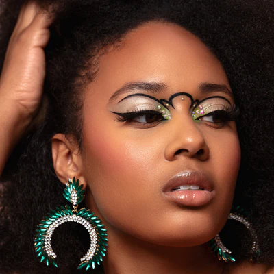 Woman with dramatic green and silver eye makeup and emerald statement earrings