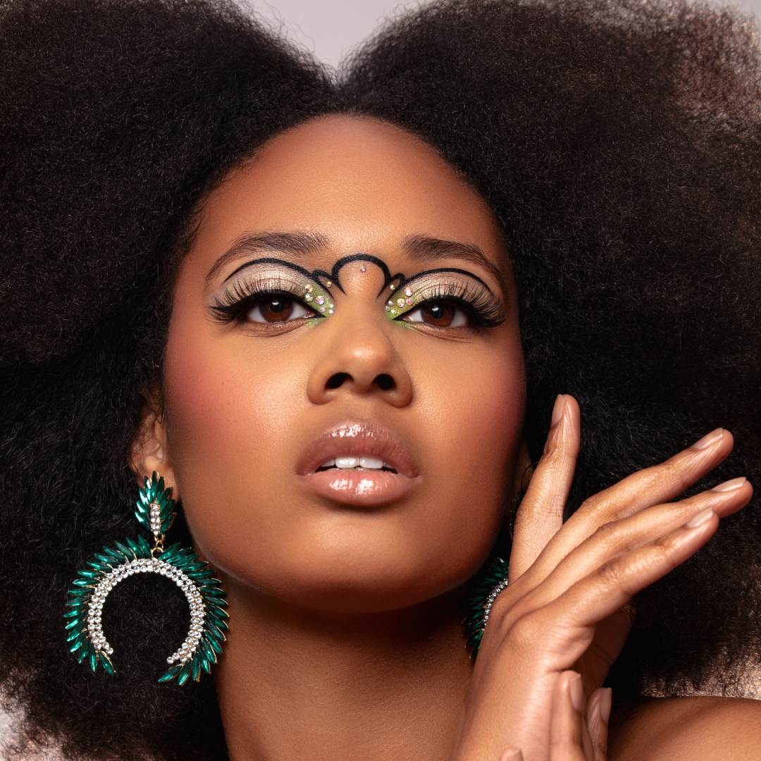 Woman with dramatic green eyeshadow and emerald statement earrings
