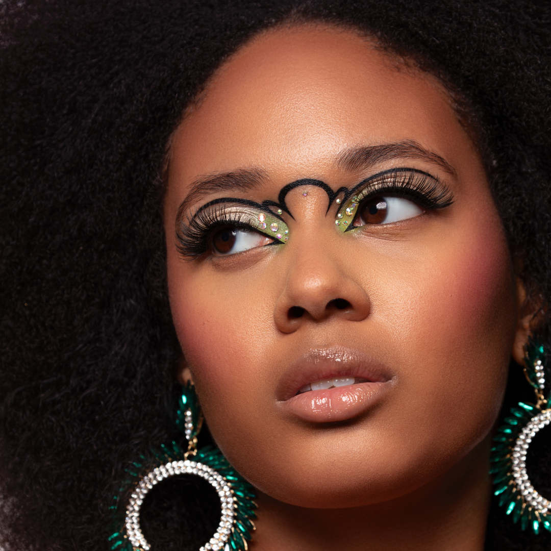 Glamorous makeup look with green eyeshadow, long lashes, and emerald earrings