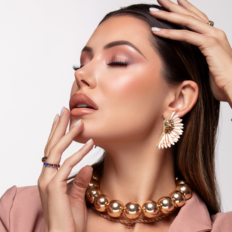 Elegant woman with closed eyes wearing gold jewelry and soft makeup