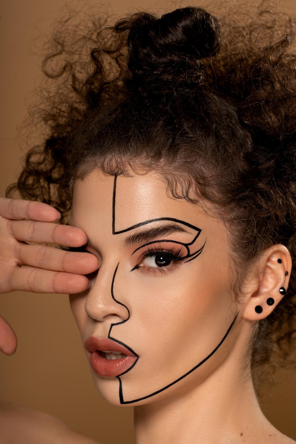 Abstract line art makeup on curly-haired person with bold graphic design