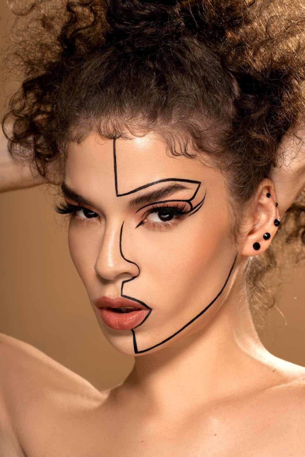 Artistic portrait with black line drawing geometric makeup on curly-haired model
